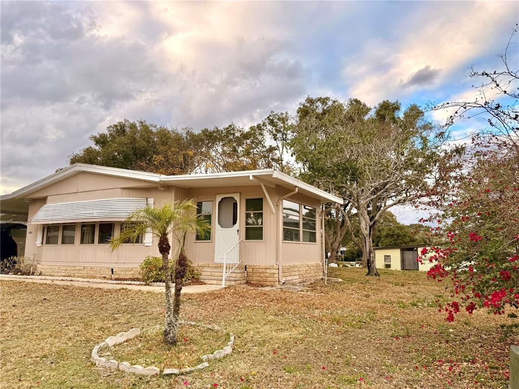 A beige mobile home with a small palm tree and a flowering bush in the yard — 3335 S CITRUS CIRCLE UNIT GE, ZELLWOOD, FL