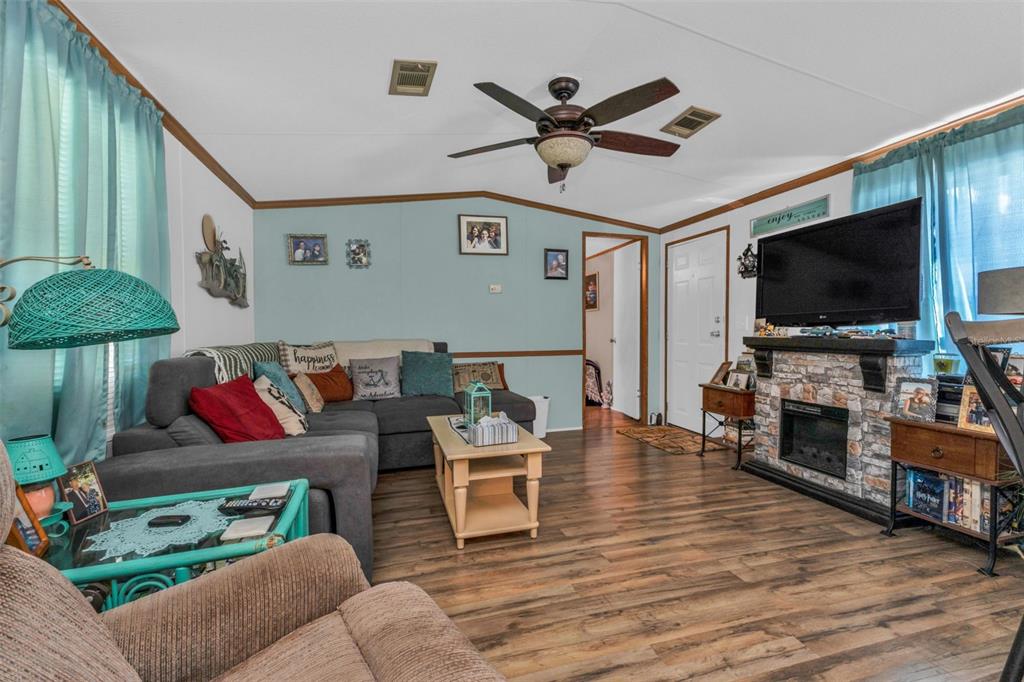A living room features a grey sectional sofa, a stone fireplace, and wood-look flooring — 1607 WOODLAWN AVENUE, PUNTA GORDA, FL