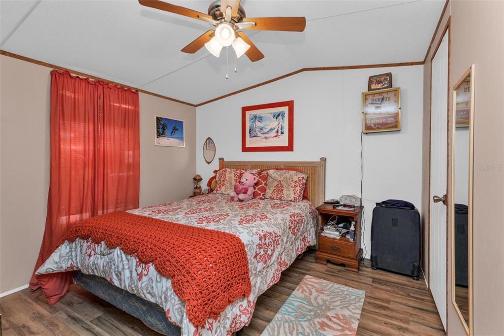 A bedroom features a bed with patterned bedding, a ceiling fan, and wood-look flooring — 1607 WOODLAWN AVENUE, PUNTA GORDA, FL