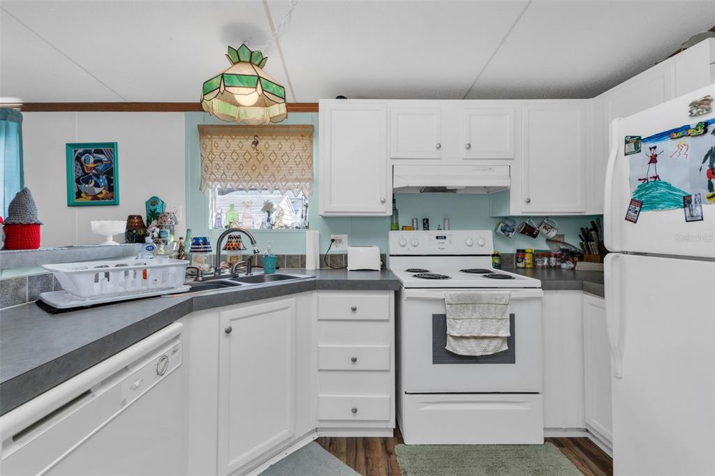A kitchen with white cabinets, a white stove, a dishwasher, and a green pendant light — 1607 WOODLAWN AVENUE, PUNTA GORDA, FL