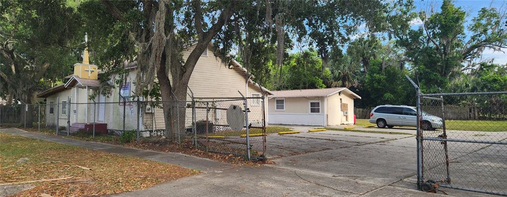 A small church building with a steeple and a separate annex sit behind a chain-link fence — 1819 W 2ND STREET, SANFORD, FL