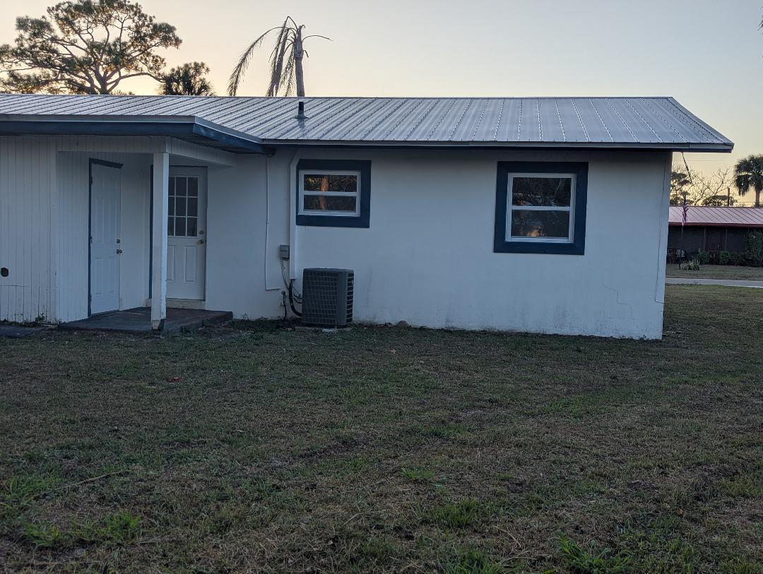 A white house with a metal roof, two windows, and an exterior air conditioning unit — 2736 Seneca Avenue, Fort Pierce FL 34945, FORT PIERCE, FL
