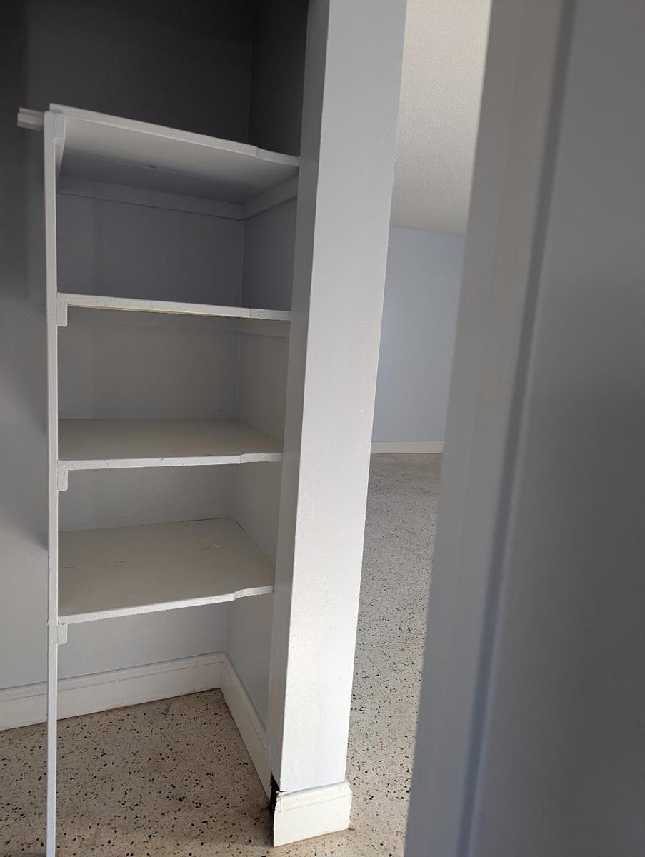 A view of built-in white shelving inside a closet next to a room with terrazzo flooring — 2736 Seneca Avenue, Fort Pierce FL 34945, FORT PIERCE, FL