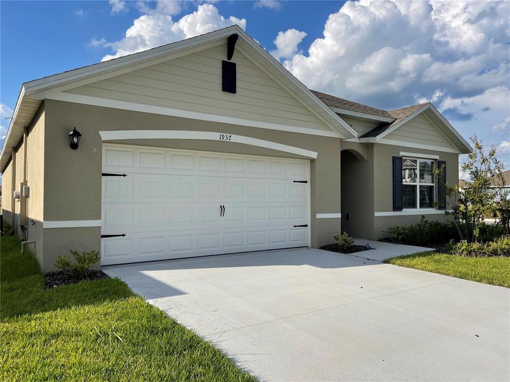 A single-story house with a beige stucco exterior, a white garage door, and a driveway — 1937 ARBOR MILL LANE, KISSIMMEE, FL