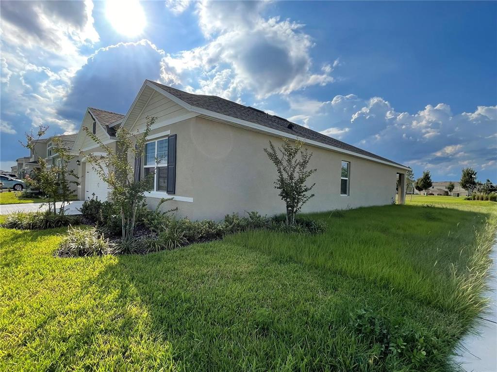 A side view of a beige single-story house with a lawn and blue sky — 1937 ARBOR MILL LANE, KISSIMMEE, FL