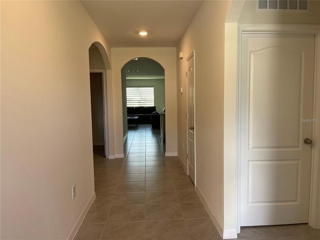 A tiled hallway leads to an arched entryway opening into a living area — 1937 ARBOR MILL LANE, KISSIMMEE, FL