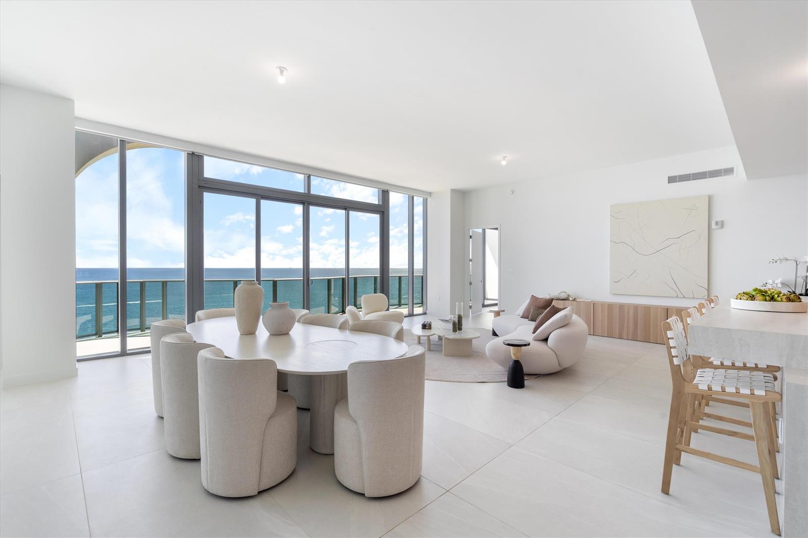 A modern, open-concept living and dining room features floor-to-ceiling windows with ocean views — 900 N Ocean Boulevard, Pompano Beach FL 33062, POMPANO BEACH, FL