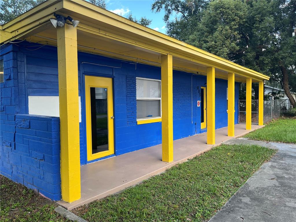 A blue brick building with a yellow-trimmed porch, yellow support columns, and yellow door frames — 805 FERGUSON DRIVE, ORLANDO, FL