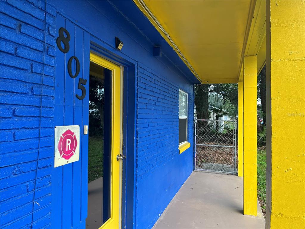 A blue brick building exterior features a yellow door, yellow support columns, and a fire sign — 805 FERGUSON DRIVE, ORLANDO, FL