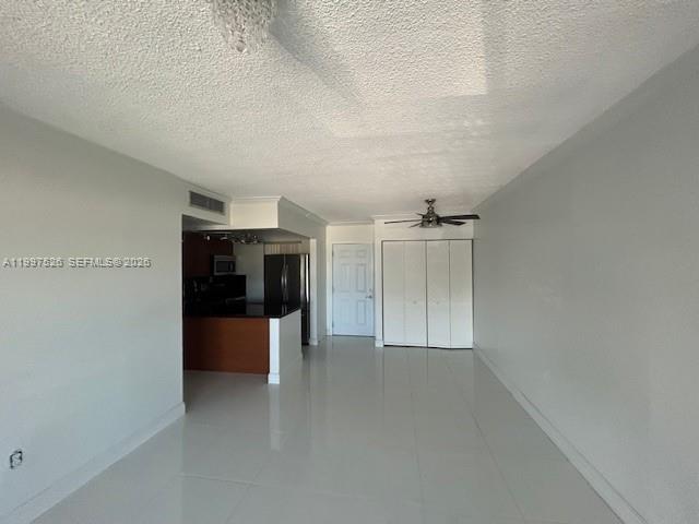 An open-concept living area features white tile floors, a ceiling fan, and a kitchen island — 1725 W 60th St # F316, Hialeah FL 33012, HIALEAH, FL