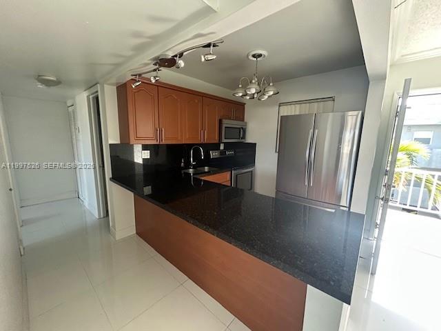 A kitchen features wooden cabinets, black countertops, stainless steel appliances, and a breakfast bar — 1725 W 60th St # F316, Hialeah FL 33012, HIALEAH, FL