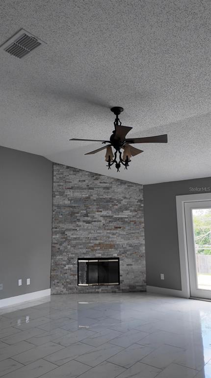 A living room features a stone fireplace, white tile flooring, and a ceiling fan — 3276 WOODGLEN DRIVE, ORANGE PARK, FL