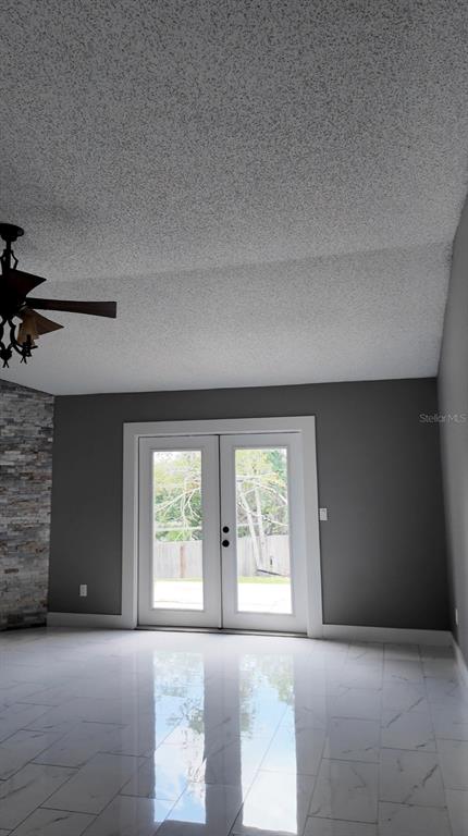 A room with white marble-look tile floors, a popcorn ceiling, and white French doors — 3276 WOODGLEN DRIVE, ORANGE PARK, FL