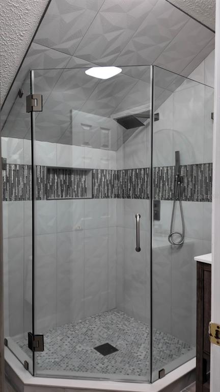 A glass-enclosed corner shower features geometric white wall tiles, a mosaic accent band, and pebble flooring — 3276 WOODGLEN DRIVE, ORANGE PARK, FL