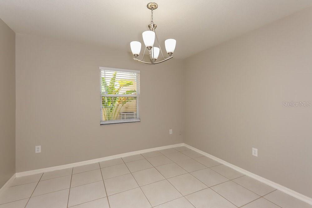 A dining room with light-colored tile flooring, beige walls, and a modern chandelier — 213 LOOKOUT DRIVE, APOLLO BEACH, FL