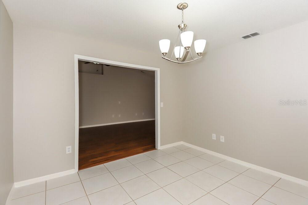 A dining room features light gray walls, white tile flooring, and a modern chandelier — 213 LOOKOUT DRIVE, APOLLO BEACH, FL