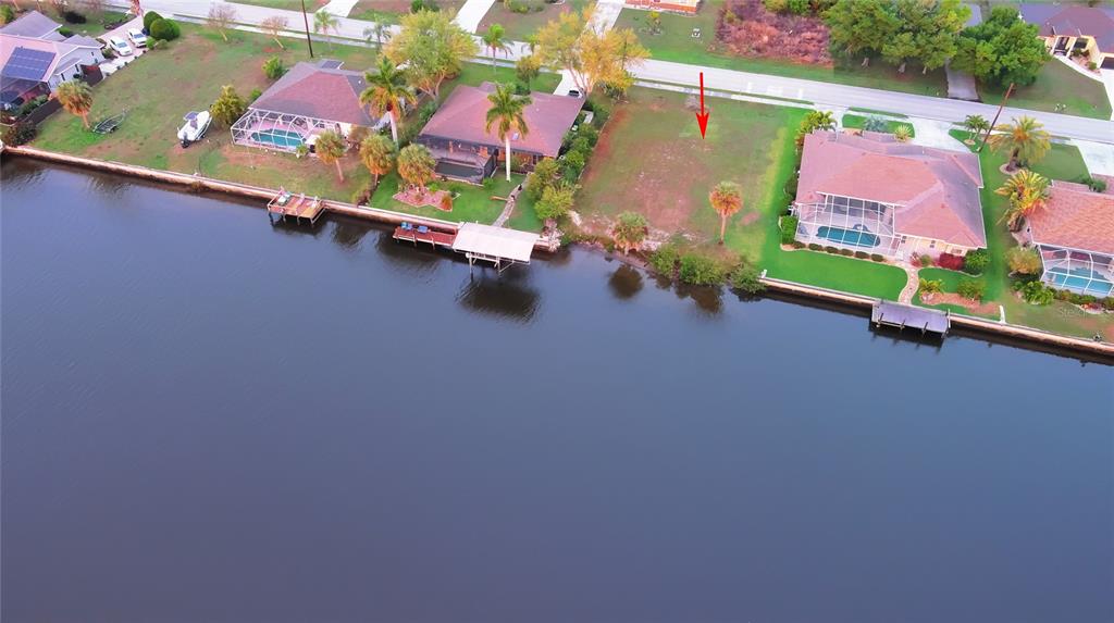 An aerial view shows a vacant waterfront lot situated between two residential homes — 3190 LAKE VIEW BOULEVARD, PORT CHARLOTTE, FL