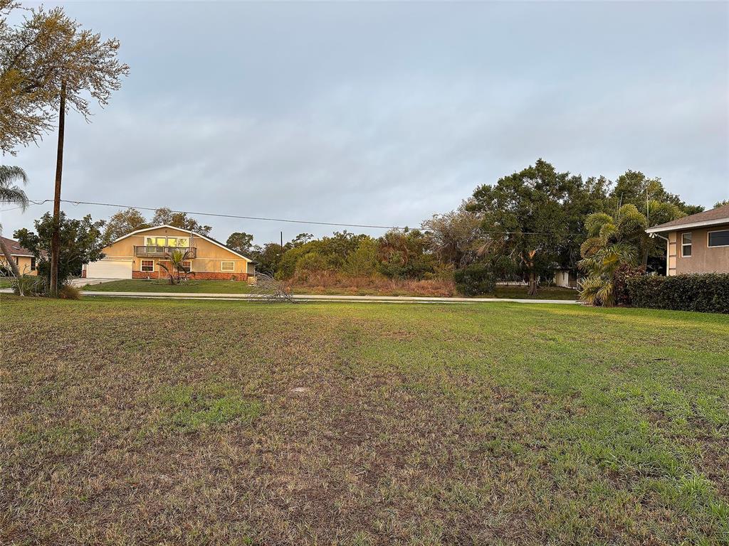 A grassy vacant lot sits in front of a residential street with neighboring houses — 3190 LAKE VIEW BOULEVARD, PORT CHARLOTTE, FL