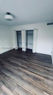 An empty room with dark wood-look flooring and two white bi-fold closet doors — 363 Washington Ave # 52, Miami Beach FL 33139, MIAMI BEACH, FL