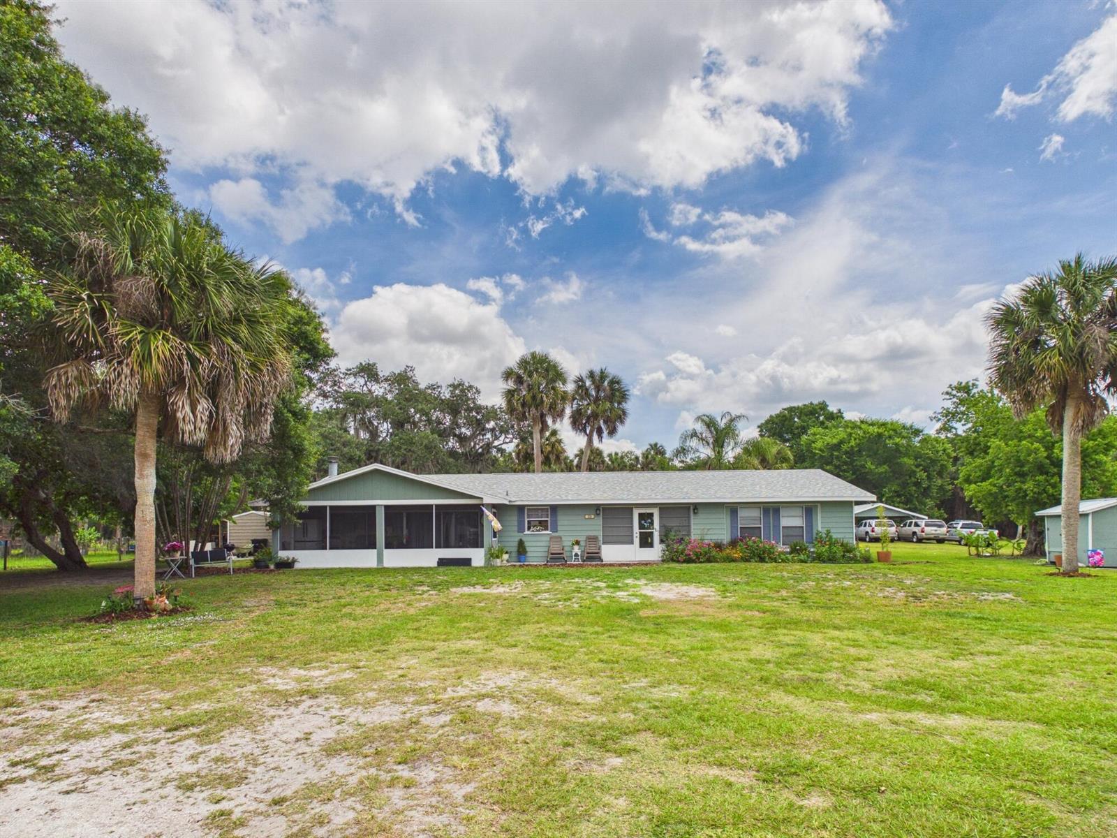 A light green single-story house with a screened porch sits on a large grassy lot — 220 SW 67th Drive, Okeechobee FL 34974, OKEECHOBEE, FL