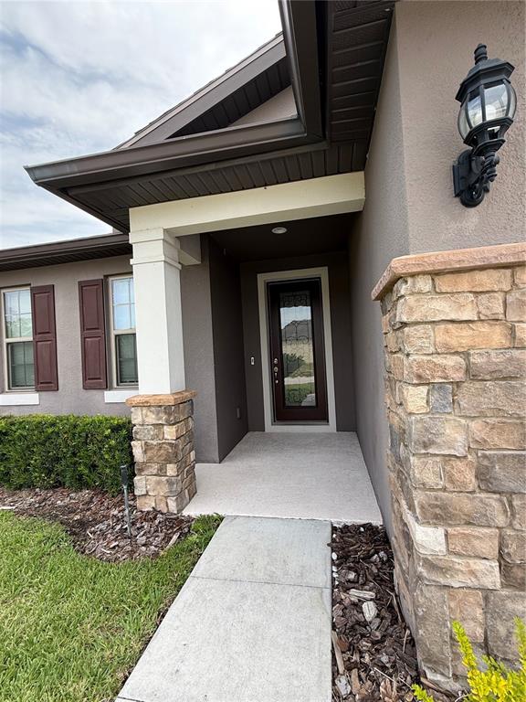 The exterior of a house features a stone-accented entryway, a dark front door, and a walkway — 8519 RINDGE ROAD, POLK CITY, FL