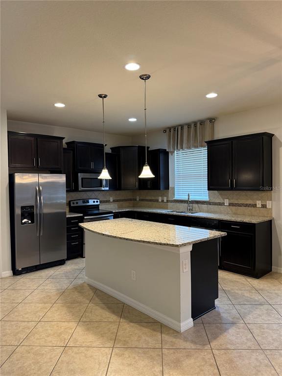 A kitchen features dark wood cabinets, granite countertops, a central island, and stainless steel appliances — 8519 RINDGE ROAD, POLK CITY, FL