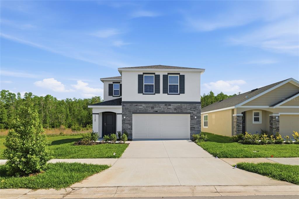 A two-story house with a white exterior, stone facade, and a two-car garage — 17786 ACORN DROP ROAD, LAND O LAKES, FL