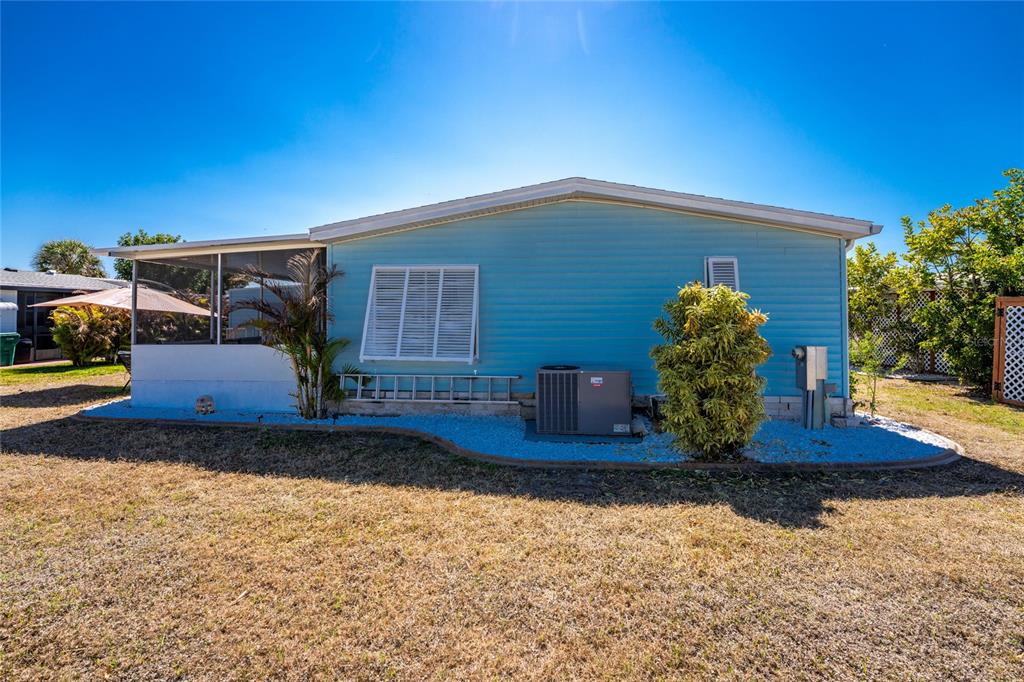 The exterior of a light blue mobile home features a screened porch and an air conditioner — 8436 NIGHTHAWK DRIVE, ENGLEWOOD, FL