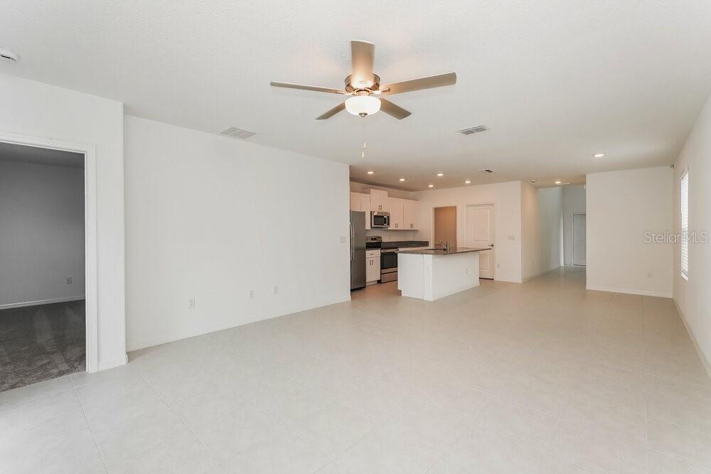 An open-concept living area features white walls, tile flooring, and a kitchen with white cabinetry — 17954 BLISSFUL STARS DRIVE, LUTZ, FL