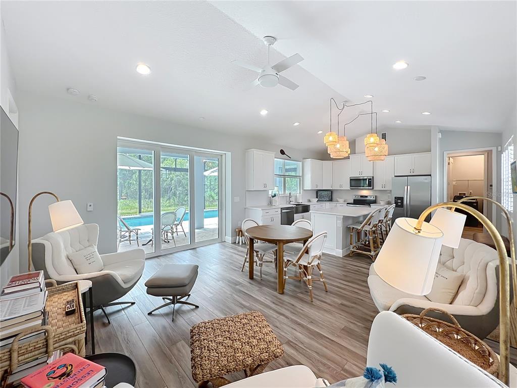 An open-concept living and dining area features light wood floors, white cabinetry, and sliding glass doors — 10220 BAY LAKE ROAD, GROVELAND, FL