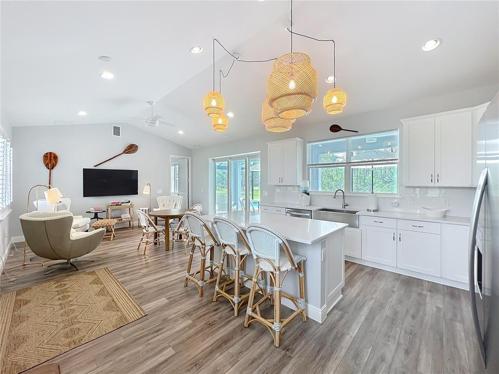 A bright open-concept kitchen and living area with white cabinetry, a central island, and wood-look flooring — 10220 BAY LAKE ROAD, GROVELAND, FL