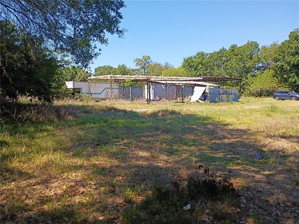 A dilapidated metal structure stands in a grassy, overgrown field near a parked car — 8615 NUNDY AVENUE, GIBSONTON, FL