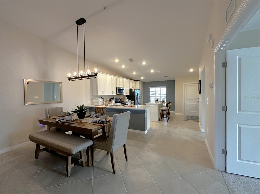 An open-concept kitchen and dining area features white cabinetry, a kitchen island, and tile flooring — 14241 HERITAGE LANDING BOULEVARD UNIT 1821, PUNTA GORDA, FL