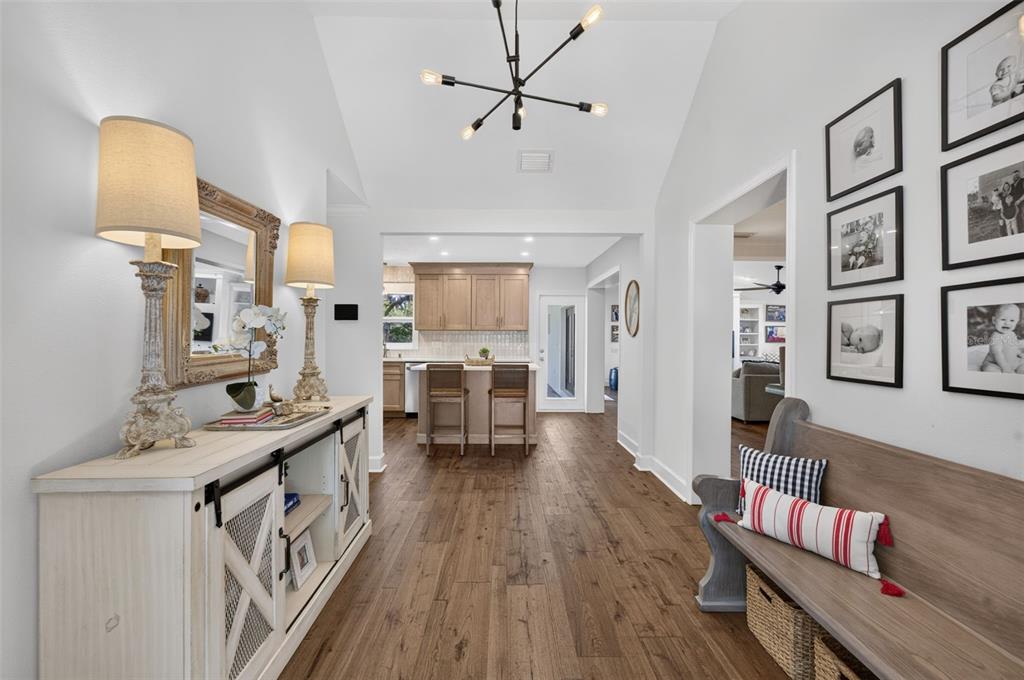A bright entryway features wood floors, a console table with lamps, and a wooden bench — 1351 ONECO AVENUE, WINTER PARK, FL