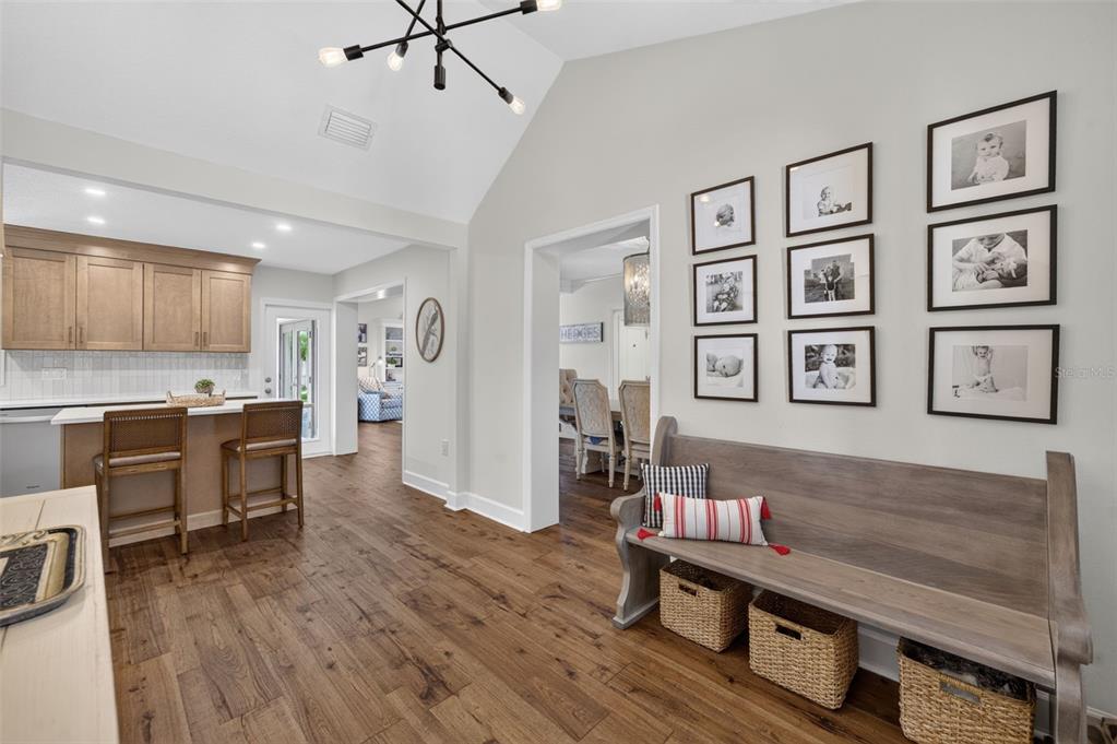 A hallway features a wooden bench with baskets, a gallery wall, and a vaulted ceiling — 1351 ONECO AVENUE, WINTER PARK, FL