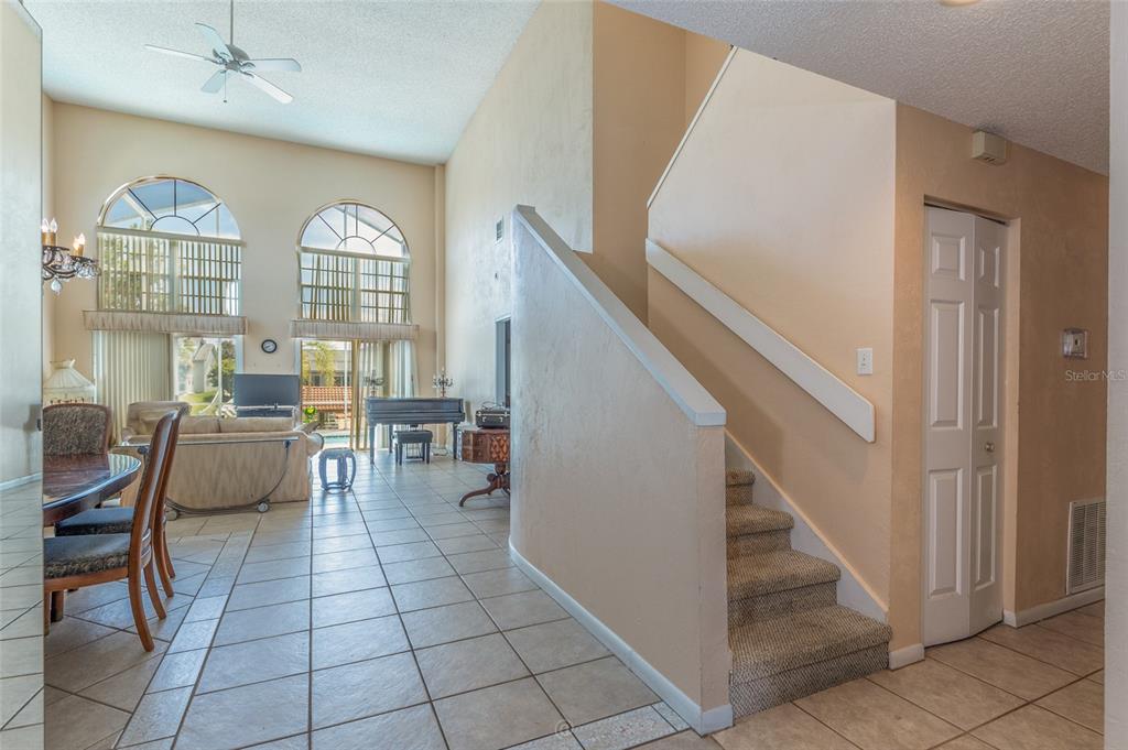 A living area with high ceilings, tiled floors, a staircase, and large arched windows — 29 CHEROKEE COURT W, PALM COAST, FL