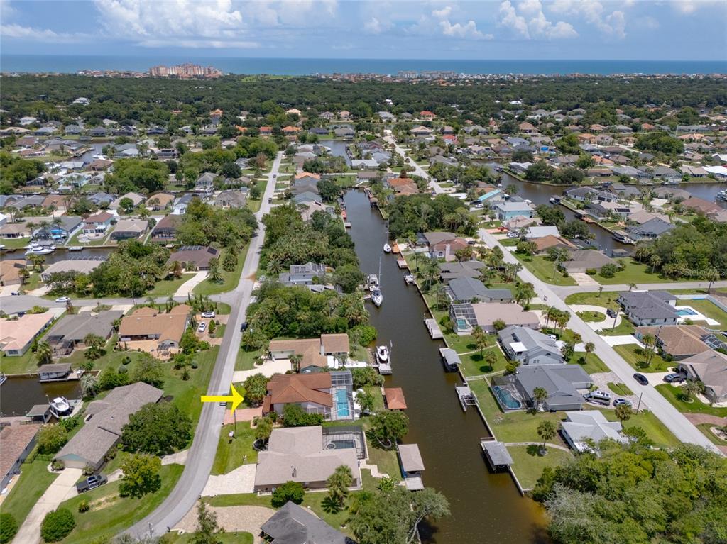 An aerial view shows a residential neighborhood with houses along a canal leading toward the ocean — 29 CHEROKEE COURT W, PALM COAST, FL
