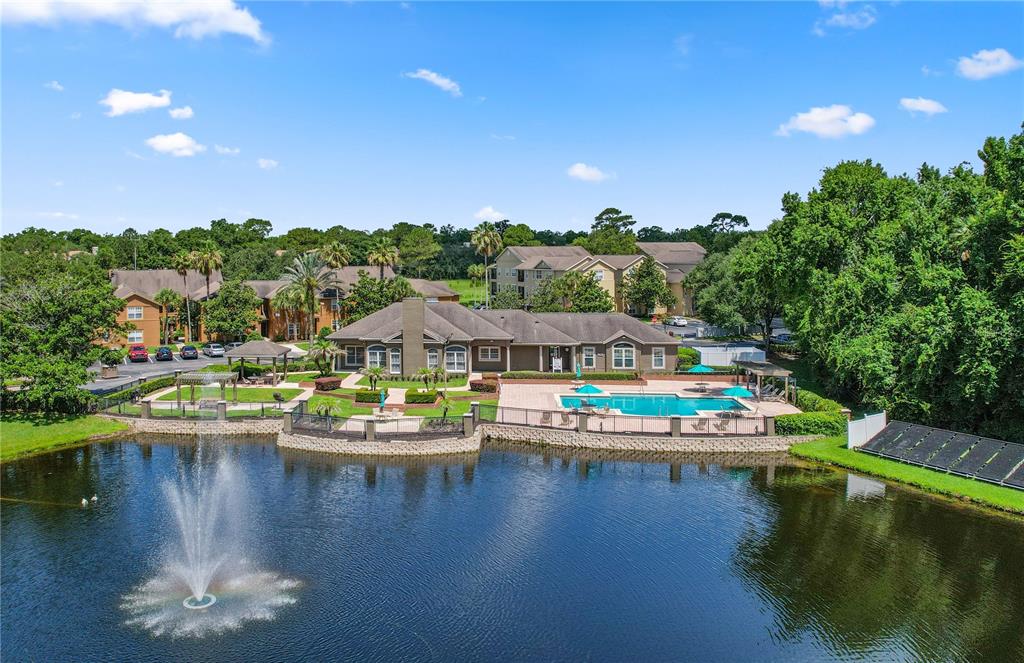 An aerial view shows a community clubhouse with a pool and fountain by a lake — 425 SUMMIT RIDGE PLACE UNIT 211, LONGWOOD, FL