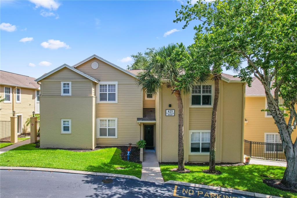 A two-story tan apartment building with a central entrance and a small lawn — 425 SUMMIT RIDGE PLACE UNIT 211, LONGWOOD, FL