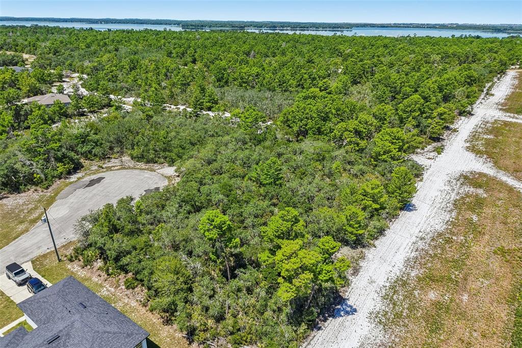 An aerial view shows a wooded, undeveloped residential lot next to a paved cul-de-sac — 1249 ALAFIA WAY, POINCIANA, FL