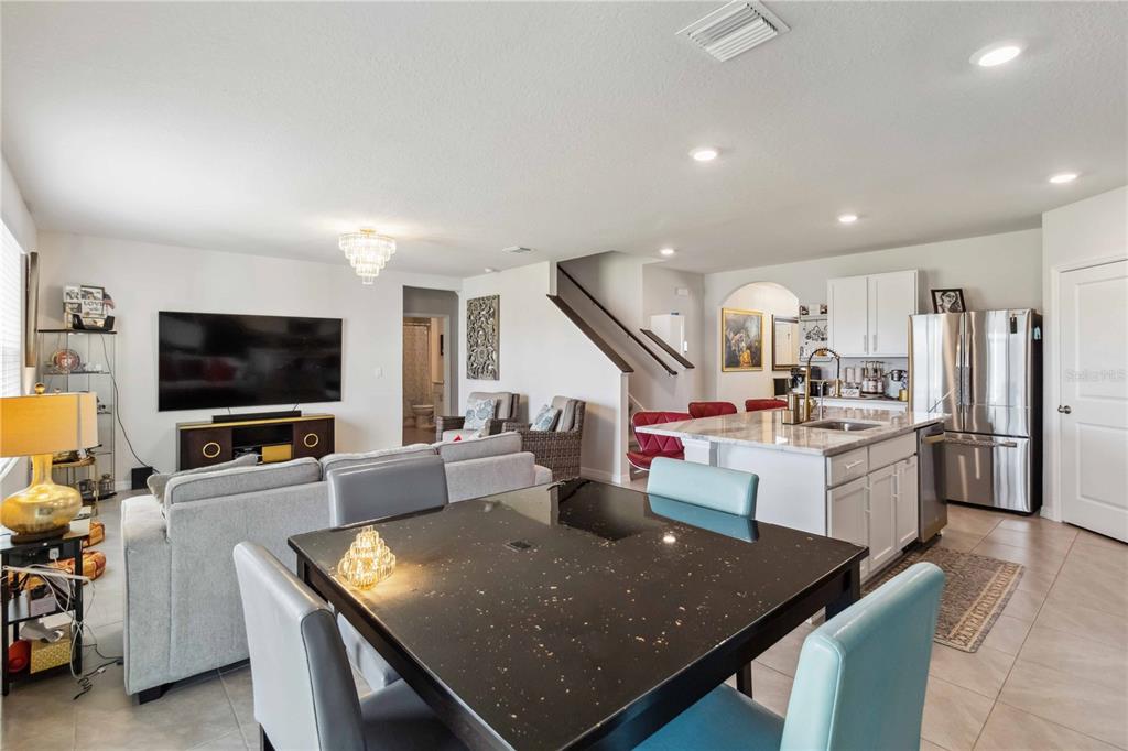An open-concept living area features a kitchen with an island, dining table, and living room — 18006 CANOPY PLACE, BRADENTON, FL