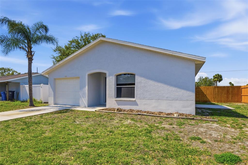 A single-story house with a white stucco exterior, a garage, and a front lawn — 6018 FLORA TERRACE, APOLLO BEACH, FL