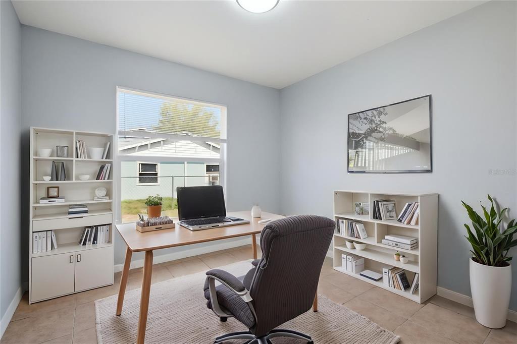 A home office features a wooden desk, two white bookshelves, and a window overlooking a yard — 6018 FLORA TERRACE, APOLLO BEACH, FL