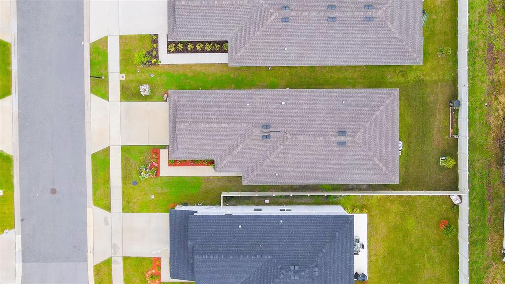 An aerial view shows three suburban houses with gray roofs and green lawns — 707 CHESTNUT LANE, AUBURNDALE, FL