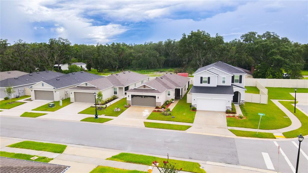 An aerial view shows a row of suburban houses with attached garages and manicured lawns — 707 CHESTNUT LANE, AUBURNDALE, FL