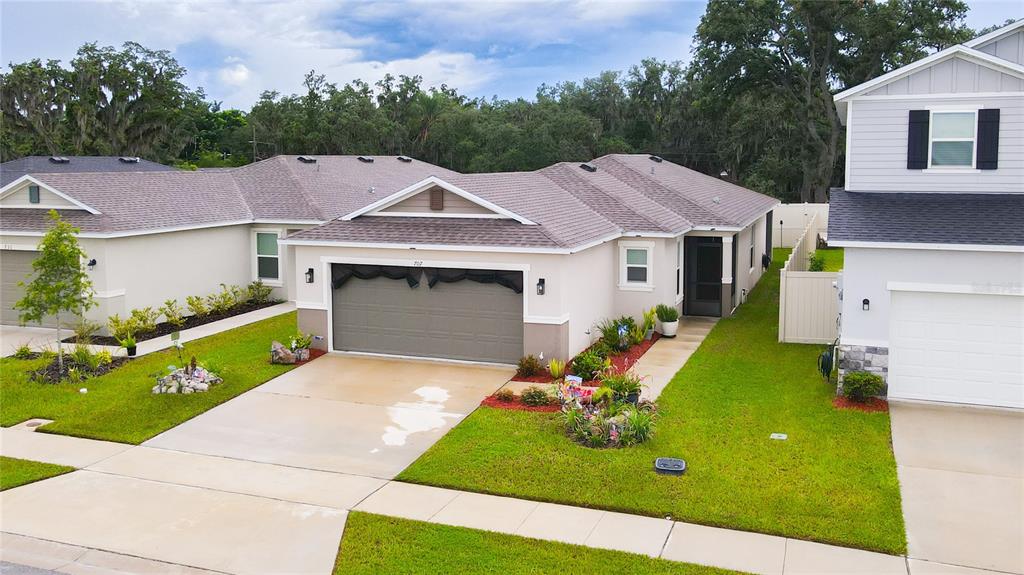 An aerial view shows the exterior of a single-story house with a two-car garage — 707 CHESTNUT LANE, AUBURNDALE, FL