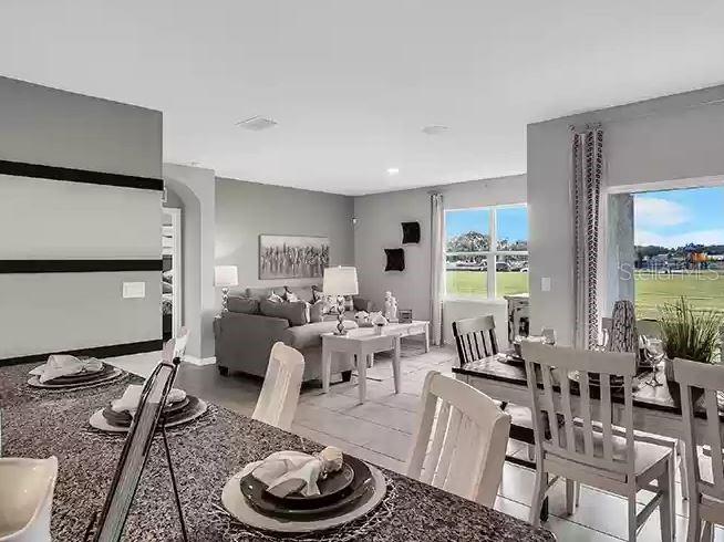 An open-concept living and dining area features gray walls, tile flooring, and a granite countertop — 3820 SWANFALLS TERRACE, SANFORD, FL