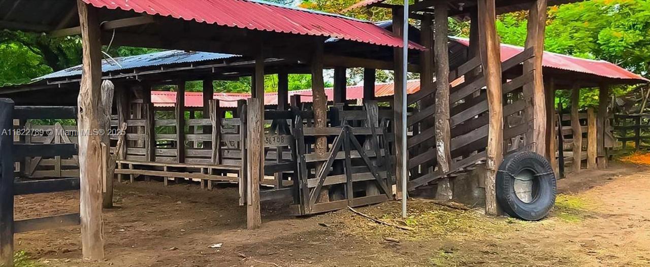 A rustic wooden cattle chute and holding pen structure with a red metal roof — SAN JUAN GRANDE La Cascabela, IL 60202, IL