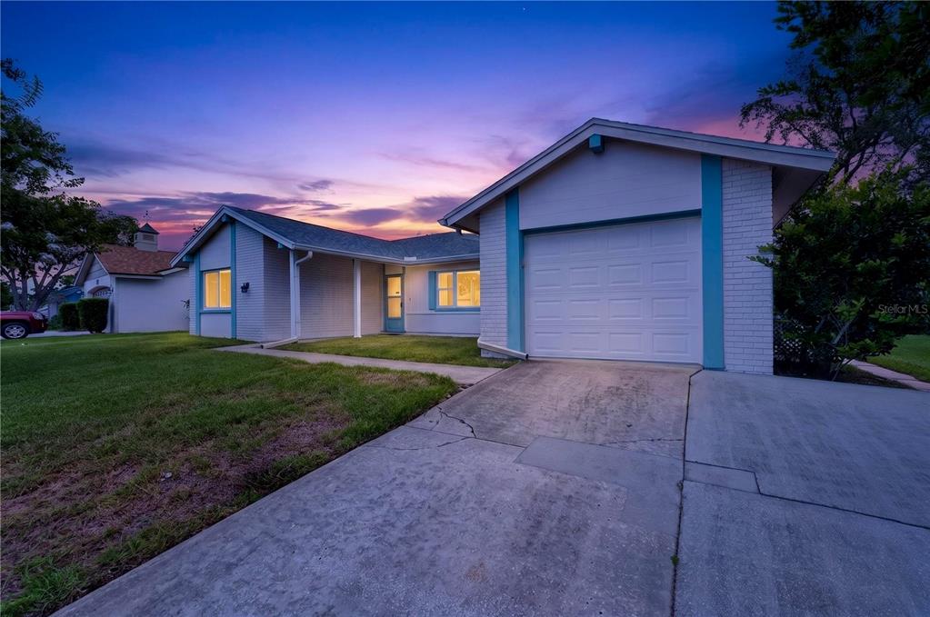 A single-story house with a white brick exterior, blue trim, and an attached garage — 13004 SERPENTINE DRIVE, HUDSON, FL