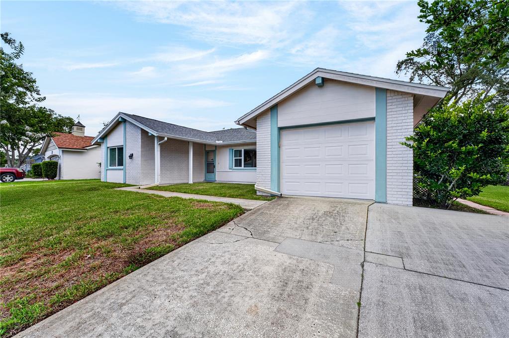 A single-story house with a white brick facade, a garage, and a concrete driveway — 13004 SERPENTINE DRIVE, HUDSON, FL